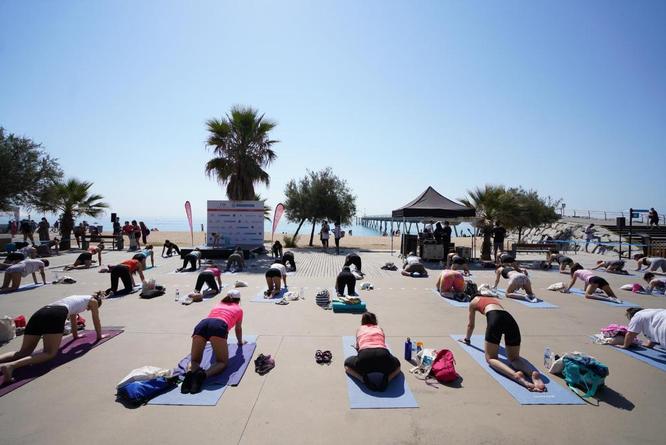 Prop d’un centenar de persones gaudeixen d’una classe grupal de ioga al passeig Marítim de Badalona